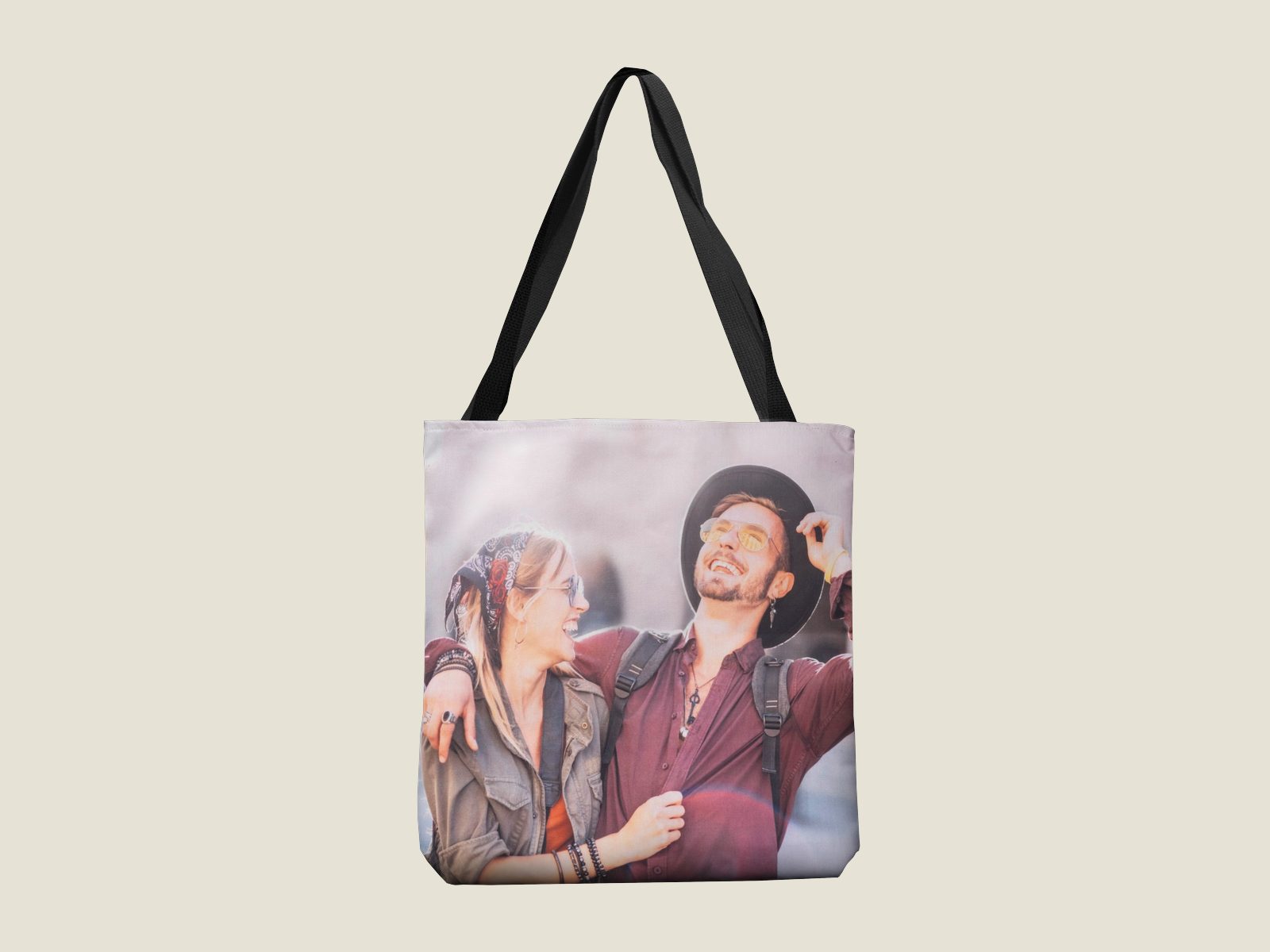 A canvas tote bag with black handles printed with a smiling couple