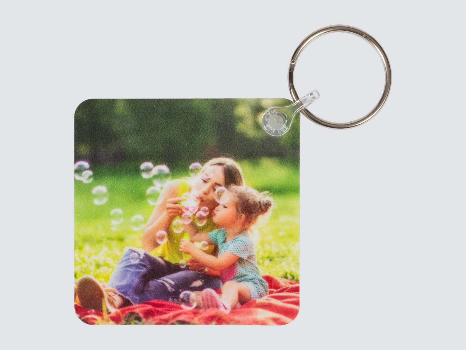 A square photo keychain of a mother and daughter blowing bubbles