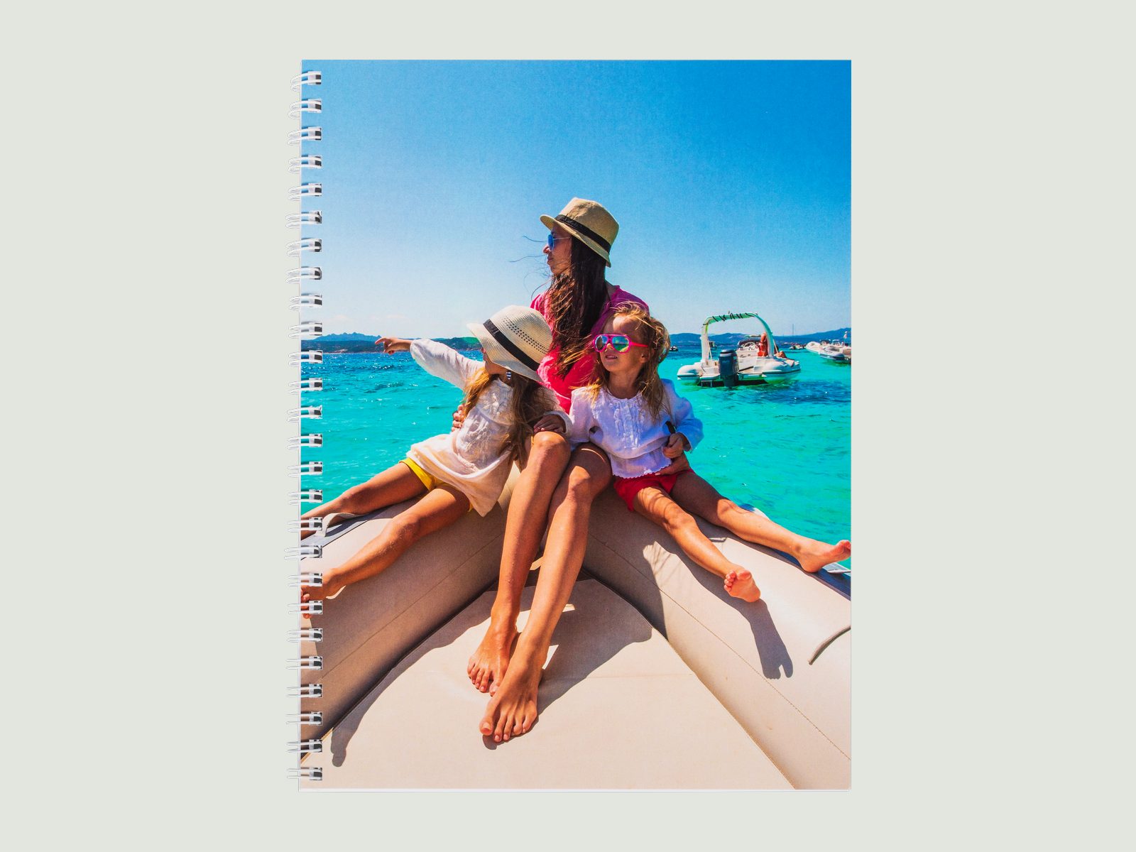 A spiral notebook with a family photo on a boat on its cover