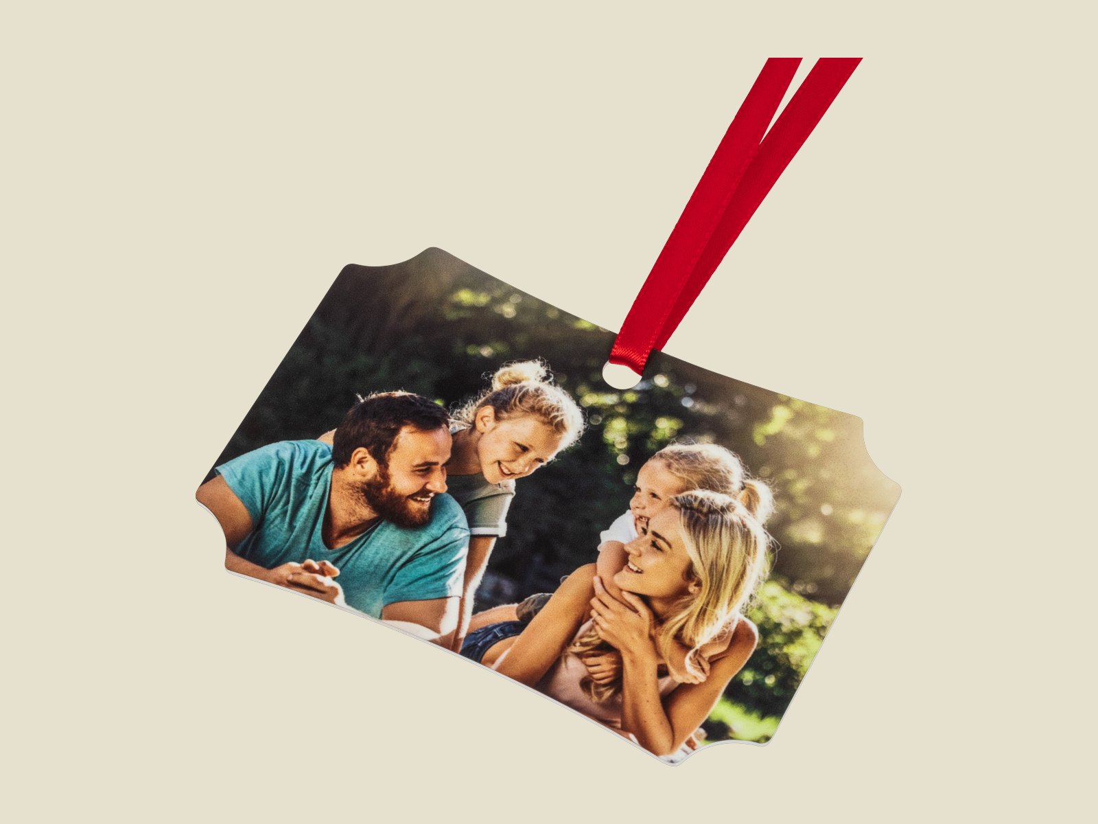 A decorative-edge metal photo ornament on a red ribbon