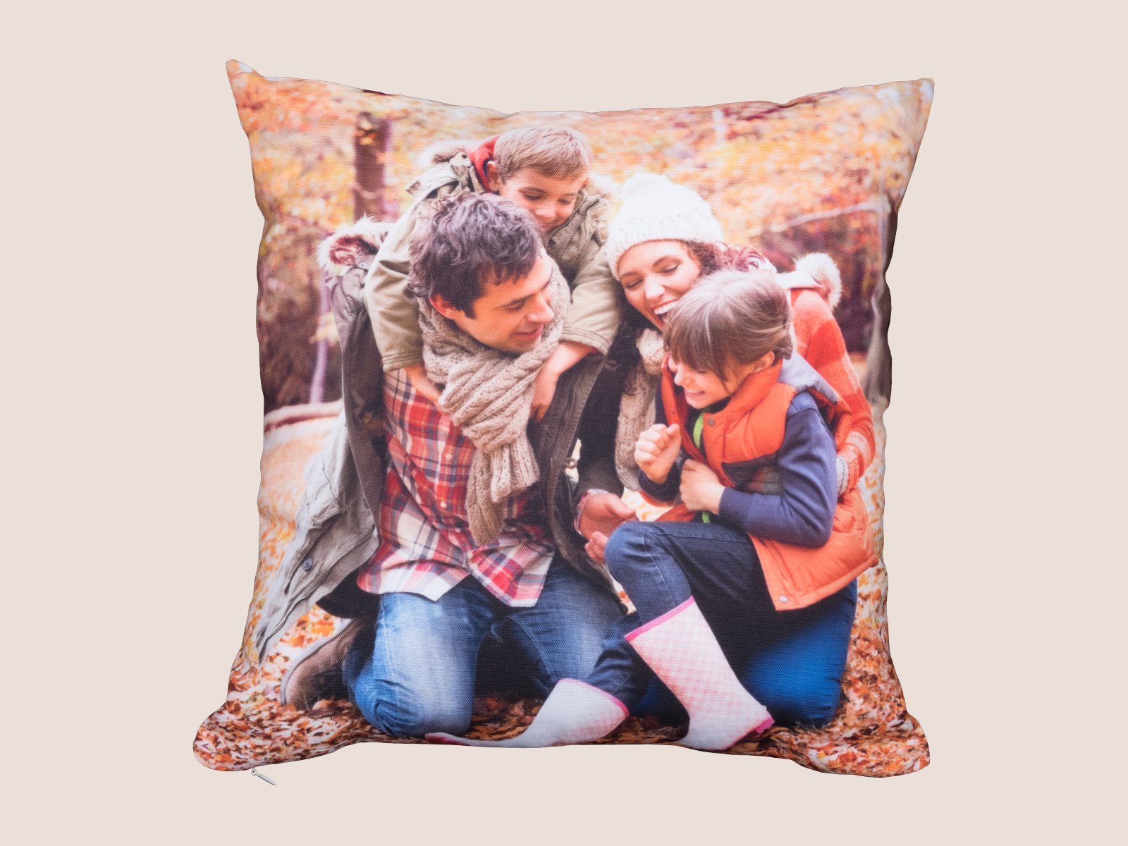 A square throw pillow printed with a family photo in autumn leaves