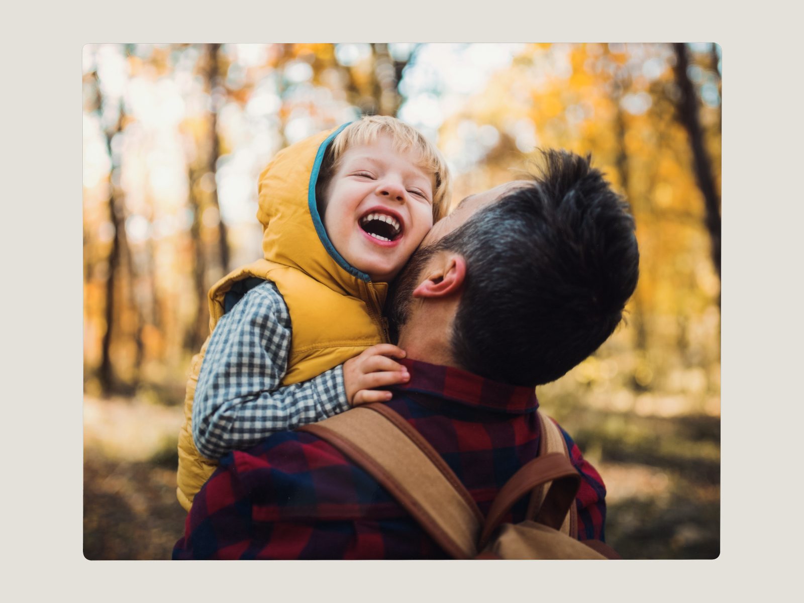 An 8x10 hardboard photo plaque of a father hugging his laughing son in autumn woods