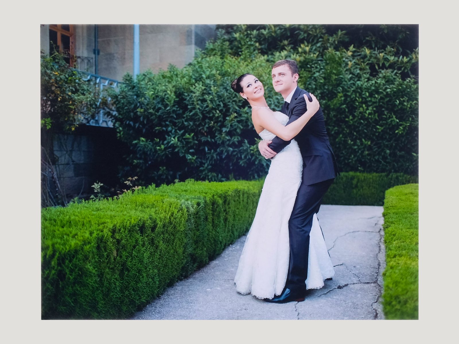 A mounted print of a bride and groom embracing in a garden